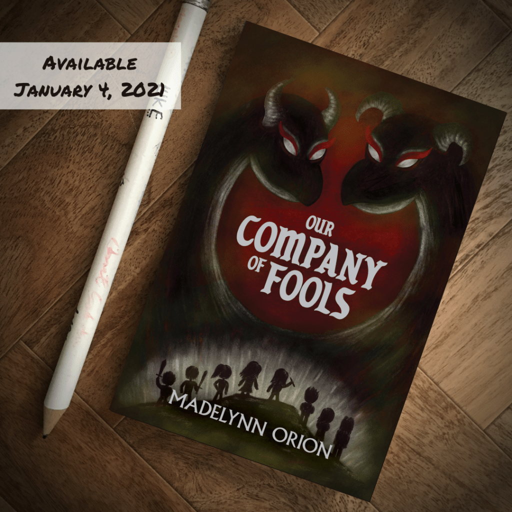 Our Company of Fools book next to a giant pencil, cover art is eight teenagers facing down two-headed dragon demon