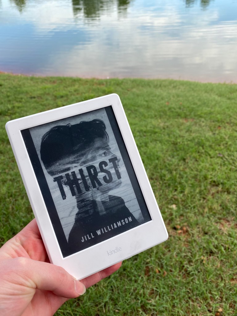 Thirst Cover on a Kindle in front of a lake