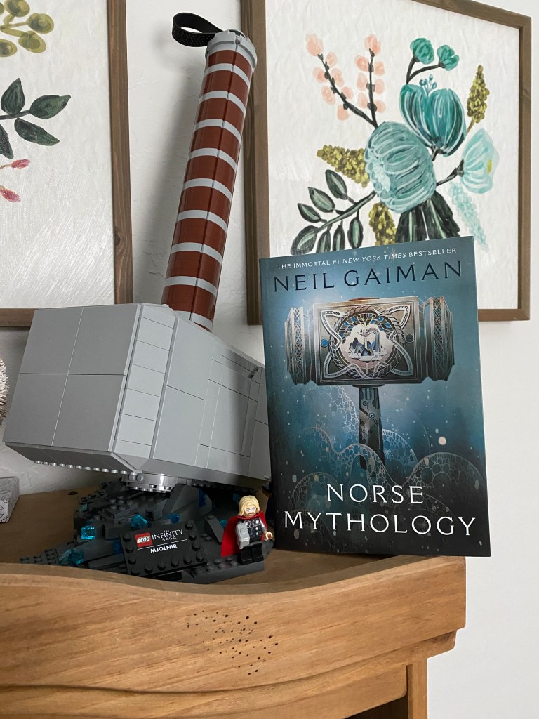Neil Gaiman's Norse Mythology next to lego mjolnir display