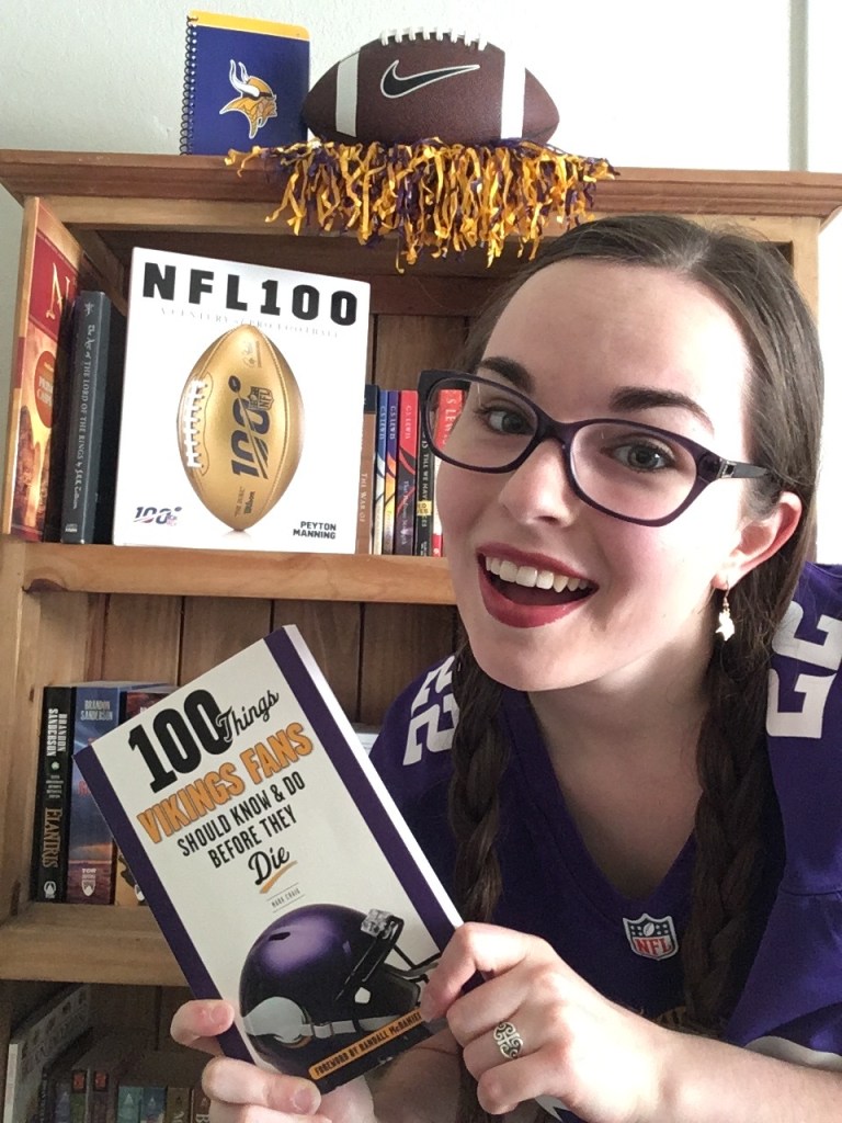 Minnesota Vikings fan holding up Minnesota Vikings book, with NFL 100 book and football in background
