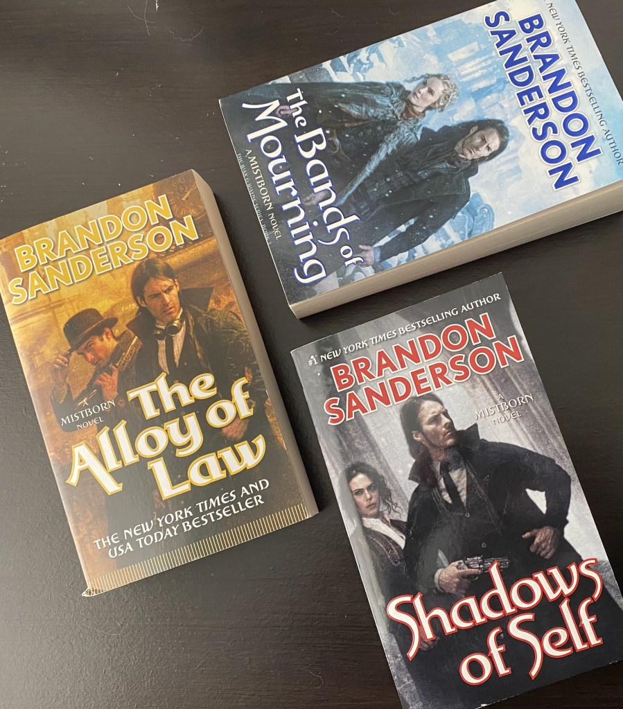 The first three Wax and Wayne books on a black shelf